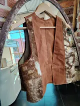 Chaleco marrón con paneles de cuero liso en el frente y laterales de piel con manchas blancas y marrones.