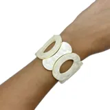 Pulsera elastizada con piezas de resina color blanco nacarado, con forma de círculos y óvalos calados.