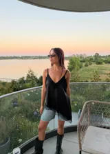 Blusa tipo lencera de satén color crema con escote en V y ruedo asimétrico, ambos decorados con encaje negro. Presenta breteles finos ajustables.