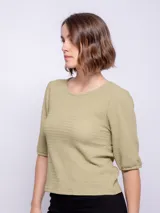 Top de manga tres cuartos color verde oliva, con cuello redondo y tejido texturizado. Las mangas son ligeramente abullonadas.