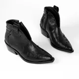 Botín de cuero vacuno color marrón oscuro, con taco de madera foliado en cuero de 5cm de altura, cierre lateral interno y horma de punta fina.