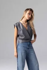 Top gris de simil cuero liviano, de escote cruzado con acceso por cierre invisible lateral. Sin mangas con espalda cerrada y frunces en hombros.