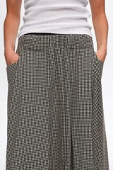 Falda midi de corte en línea A color negro con diseño de cuadros vichy blancos y negros, con bolsillos laterales y cintura elástica.