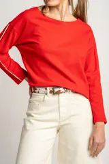 Sweater rojo de algodón con textura y corte oversize. Tiene mangas largas con dos rayas blancas en los brazos.