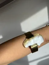 Brazalete rígido hecho a mano en bronce dorado con pieza irregular de nácar engarzada.