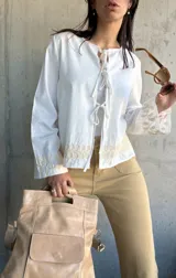 Chaqueta blanca de algodón con bordados florales en puños y ruedo, escote con lazos y mangas largas acampanadas.