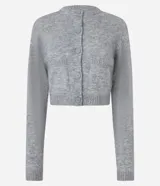 Cardigan cropped de punto color gris, con cuello redondo, manga larga, cierre frontal con botones y dos bolsillos delanteros. Presenta terminaciones acanaladas en puños y bajo.