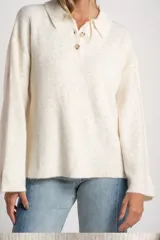 Sweater de punto con cuello polo y cierre frontal de tres botones. Presenta un diseño de corte oversize, mangas largas y textura acanalada.