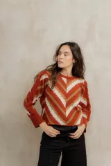 Sweater de punto jacquard con diseño de chevron en tonos celeste y marrón. Presenta cuello redondo, corte holgado y mangas largas con hombros abullonados.