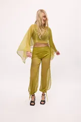 Pantalón ancho de seda color amarillo, estilo parachute o globo, con talle alto y cordones ajustables en los tobillos.