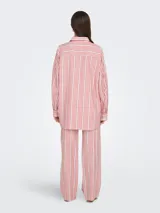 Camisa de manga larga con cuello clásico y cierre frontal de botones. Diseño holgado con bolsillo en el pecho. Estampado de rayas verticales en rojo, blanco y negro.