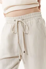 Pantalón babucha color beige de lino y viscosa, con elástico en la cintura y bolsillos laterales.