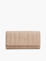Billetera Tommy Hilfiger de poliuretano color beige, con diseño acolchado, cierre de solapa y logo metálico dorado TH en el frente.