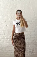 Remera blanca ajustada al cuerpo con estampado de moño de encaje negro en el centro.