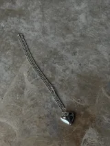 Collar corto de cadena plateada con dije de corazón tridimensional y brillante.