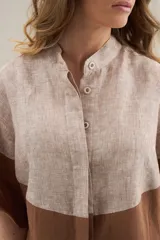 Camisa larga de lino con diseño bicolor en tonos beige y marrón, cuello mao y mangas cortas.
