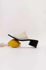 Sandalia de cuero vacuno color marrón oscuro, con faja ancha y punta cuadrada. Presenta talón abierto y taco bajo y grueso.