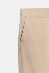 Pantalón de tiro alto color beige, estilo palazzo o ancho, confeccionado en mezcla de viscosa. Presenta bolsillos laterales y cierre frontal con cremallera y botón.