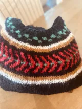 Sweater negro tejido a mano en mohair, con cuello redondo y diseño con motivos geométricos en blanco, rojo, verde y amarillo.