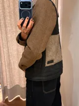 Campera de diseño híbrido con frente acolchado en color tostado, solapas y cuello en tejido de lana con patrón de cuadros tipo príncipe de gales, y mangas en paño de lana color azul marino. Cuenta con cierre frontal de botones.