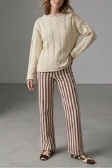 Sweater de tejido de punto con diseño de trenzas verticales, cuello redondo y mangas largas. Presenta un calce holgado y cómodo.