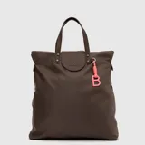 Mochila convertible en bolso tipo tote de la marca Bubba, color marrón, con acabado impermeable. Presenta un diseño minimalista con solapa frontal, asas superiores y un llavero decorativo con la letra B en color rosado.