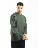 Buzo de punto liso color negro, con cuello redondo y puños y ruedo acanalados. Se lleva sobre una camisa celeste de vestir.