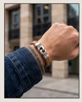 Pulsera trenzada de cuerina color marrón con cierre de acero inoxidable con diseño grabado.