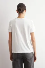 Remera blanca de manga corta con estampado frontal de diseño damasco floral en tonos bordó y marrón.