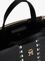 Cartera tipo satchel de Tommy Hilfiger en color negro, confeccionada en material texturizado. Presenta doble asa superior, correa ajustable extraíble y un diseño frontal con dos bandas verticales decorativas y el logo metálico TH en el centro.
