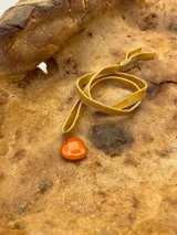 Gargantilla con cinta de terciopelo color beige y dije de nácar con forma de corazón.