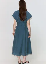 Vestido midi de corte recto color azul, con cuello camisero, mangas cortas y cierre delantero con botones ocultos. Incluye un cinturón ajustable del mismo tejido para anudar en la cintura.