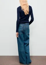 Pantalón de jean estilo wide leg con tiro medio, cierre frontal de cremallera y botón, cinco bolsillos y detalle de tachuelas en la cintura.