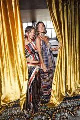 Vestido largo de encaje y transparencias color marrón, con escote profundo halter, frunces en el cuerpo, espalda abierta y tiras largas estampadas para atar al cuello.