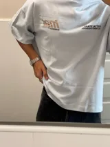 Remera color crema de corte holgado con mangas cortas y estampado en la espalda con el logo de la marca Ittai en color marrón.