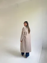 Tapado largo de paño en color beige, con solapas anchas, cierre frontal de un botón y diseño estructurado.