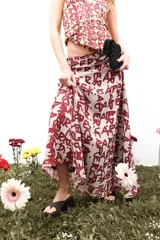 Falda larga de gasa con estampado tipográfico en color bordó sobre fondo beige. Presenta una silueta fluida y cierre lateral oculto.