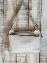 Bolso de hombro color beige con textura de cuero grabado tipo cocodrilo. Presenta dos bolsillos frontales con solapa y cierres metálicos, y una correa ancha ajustable con ojales metálicos.