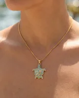 Collar de bronce dorado con cadena finita y dije en forma de tortuga con incrustaciones de piedras turquesas.