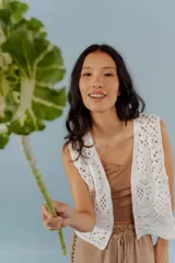 Chaleco negro de tejido de punto abierto, sin mangas y sin cierre, con cuello solapa.