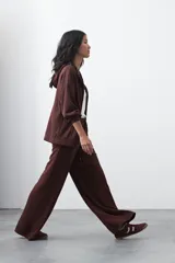 Pantalón de corte holgado y pierna ancha, con cintura elástica ajustable mediante cordón. Presenta bolsillos laterales y costuras verticales decorativas que recorren el frente de las piernas.