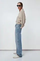 Pantalón de jean celeste de tiro alto, corte recto y largo hasta el tobillo. Tiene cinco bolsillos, trabillas en la cintura, efecto lavado y cierre frontal con cremallera y botón.