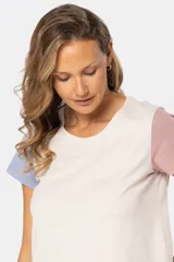 Remera de manga corta con cuello redondo y diseño de bloques de color. El cuerpo es beige, la manga izquierda es azul claro y la manga derecha es rosada.