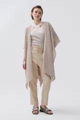 Pantalón chino color beige confeccionado en lino metalizado, de tiro medio-alto y pierna recta. Cuenta con bolsillos laterales y en la espalda.