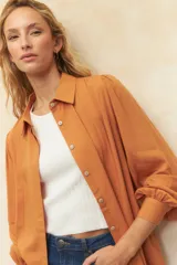 Camisa blanca de mangas abullonadas con sutiles plisados frontales, cuello clásico y corte relajado.