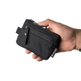 Billetera tipo pouch color negro, fabricada en material impermeable xPac X21. Cuenta con cierre principal, bolsillo frontal con cierre y tiradores ergonómicos. Incluye tecnología de bloqueo RFID.