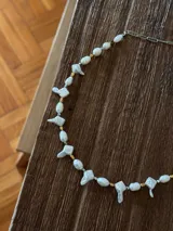 Collar corto de perlas de río y perlas barrocas con formas irregulares, intercaladas con pequeñas piezas metálicas en tonos dorado y plateado. Cuenta con cadena de extensión para regular el largo.