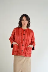 Campera corta de nylon impermeable con estampado de rayas verticales rojas y blancas, cuello redondo, cierre frontal con botones de madera, mangas largas y bolsillos de parche.