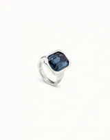 Anillo plateado con un cristal facetado rectangular de color azul oscuro. El diseño está inspirado en un clavo.