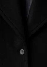 Abrigo de lana de corte oversize, color negro, con cuello de solapa con muesca, cierre frontal de botones y manga larga. Cuenta con forro interior.